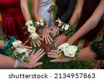 Small photo of A circle of wrist corsages before a school prom dance. Beautiful group of girls wearing traditional flowers at the homecoming dance