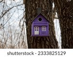 Wooden purple birdhouse on a tree close-up. Shelter and nest for birds.