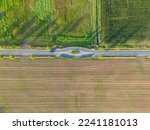 Panoramic top view parts of different agricultural fields.Yellow-green corn field and fields with other green agricultural plants. Dirt road between fields. High quality photo