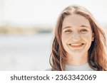 Small photo of Meet a cheerful and captivating millennial woman with enchanting brown eyes, long loose brown hair, and a playful, roguish smile. Her vibrant personality shines against the backdrop of a beautiful