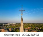 Small photo of Captured from an aerial perspective, this image features the spire of a church with an ornate cross perched atop, reaching towards the vast blue sky. The spire stands as a poignant symbol of faith and