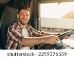 Small photo of Professional middle aged truck driver in casual clothes driving truck vehicle going for a long transportation route.