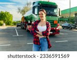 Small photo of Junior female truck driver standing in front of her truck after she successfully completed her first tour