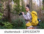 Small photo of A curly-haired forest wanderer, enjoying the serene atmosphere of an autumn forest trail, accompanied by her trusty binoculars.