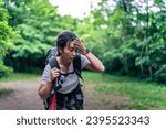 Small photo of Young Asian woman is tired of the strenuous trail and carrying heavy equipment for a long time, trying to catch a breath