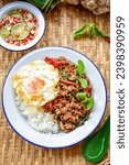 Small photo of Rice topped with stir fried Thai basil with minced pork and fried egg, pad ka praow moo sap, top view food