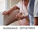 Mature female in elderly care facility gets help from hospital personnel nurse. Senior woman with aged wrinkled skin and care giver, hands close up. Grand mother everyday life. Background, copy space.