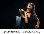 Black friday sale concept. Shopping woman holding grey bag isolated on dark background in holiday
