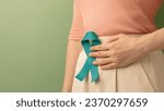 Small photo of Ovarian and Cervical Cancer Awareness. Woman Holding Teal Ribbon on Lower Abdomen, Uterus, Female Reproductive System, Women's Health, PCOS and Gynecology