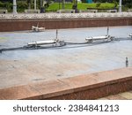 Small photo of Empty fountain in a city park. Dehumidification. Cleaning the fountain with a hose. The device of the fountain. Pipes for water supply. Water hoses. Modern technologies. Infrastructure maintenance.
