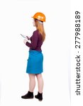 Small photo of Backview of business woman in construction helmet stands and enjoys tablet or using a mobile phone. Standing young girl. Rear view people collection. Engineer scorekeeper at work.
