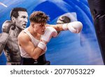 Small photo of HELSINKI, FINLAND – NOVEMBER 11 2021: Professional boxer Jamil Elo (Jamil Mahdi) punching the heavy bag at Ringside Gym. A painting of the European lightweight champion Edis Tatli in the background.