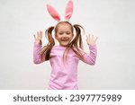 Small photo of A funny laughing child in the guise of a rabbit on white bacground. The year according to the zodiac sign of the Eastern calendar. Easter Greeting poster