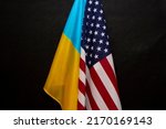 Small photo of The flag of Ukraine and the flag of America are joined together on a black background, close-up, bends and waves on the flags. Concept: joint meeting, lend-lease assistance.