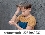 Small photo of Boy in handcuffs, emotional portrait, gray background. Concept: juvenile delinquent, juvenile delinquent.