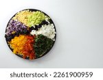 Finely chopped vegetables, orzo pasta, mozzarella cheese, basil and olives lie on a large plate. Ingredients for preparing a Mediterranean salad with orzo pasta.