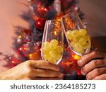 Small photo of New Year's Tradition: Twelve Grapes on the Glasses and a Festive Tree.