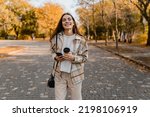 candid attractive young smiling woman walking in autumn park with coffee wearing checkered coat, happy mood, fashion style trend