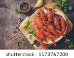 Boiled crawfish, lemon and parsley on a wooden table. Appetizer protein, the concept of healthy eating. Top view flat lay background. Copy space. Toned image.