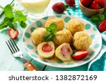 Cottage cheese dumplings with fresh strawberry, served with sour-honey sauce, delicious summer dessert on the kitchen wooden table. 
