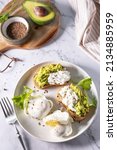 Small photo of Easter breakfast or brunch. Delicious breakfast or snack - poached egg and cream cheese toast whole grain rye bread, avocado on a marble tabletop.
