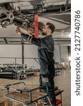 Bearded man maintenance technician tightening bolt with wrench while repairing aircraft in hangar
