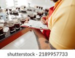 Cropped photo of male worker making notes before coffee tasting standing near table with coffee glasses and beans