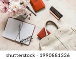 Women's desktop with a bag, peony flowers, notepad, organizer, phone. Light background, top view, business concept        