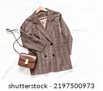 Checkered jacket in English style and brown leather cross body bag on a light background, top view   