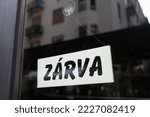 Small photo of Sign in the shop window behind a pane of glass saying 'zarva' which means 'closed'. the shop is closed. end of business. closure of business. modern font.