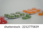 Small photo of Fruity and green colored throat lozenges in a pack, yellow and red lozenges in the background