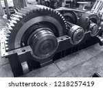 large gearbox open, showing the gears, the whole set attached to a shaft with a cap, industrial environment, photo in black and white with bluish tone