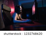 Small photo of A cute female gamer girl sits in a cozy room behind a computer and plays games. Woman live streaming computer video games to her fans and wiggle hand to them. Streamer and gamer concept.