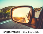 Beautiful sunset in sideview car mirror on mountain road