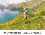 backpacker tourist woman trekking with poles by lakefront of Lake Robiei and its dam. Swiss reservoir in Maggia Valley of Ticino canton. Top of tramway station from San Carlo town of Switzerland.