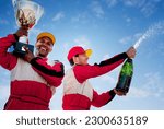 Small photo of Racers holding trophy and champagne