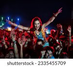 Small photo of Cheering woman on man shoulders at music festival