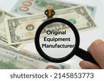 Small photo of Original Equipment Manufacturer.Magnifying glass showing the words.Background of banknotes and coins.basic concepts of finance.Business theme.Financial terms.