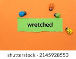 Small photo of wretched.The word is written on a slip of paper. Emotional nouns, feeling words, emotional phrases. Positive or negative attitudes.