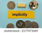 Small photo of implicitly.The word is written on a slip of paper,on colored background. professional terms of finance, business words, economic phrases. concept of economy.