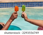 Close up of friends holding ice lolly popsicles in the swimming pool, beat heat