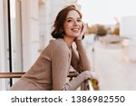 Adorable dark-eyed girl laughing at balcony. Photo of cheerful caucasian woman with beautiful smile.