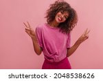 Small photo of Medium-sized image of sincere young Afro woman with open bright smile and style on pink background. It spreads positive energy and benevolence, making hair frizzy and frizzy. Beauty concept