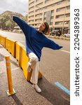 Small photo of In full growth, funny young caucasian woman, closing eyes, waves arms to sides standing on street. Brown-haired with bob haircut wears casual clothes. Lifestyle concept