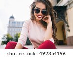 Bottom view of attractive student girl in sunglasses with snow-white smile, long hairstyle and vinous lips chilling in city. 