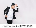 Small photo of Attractive young man in suit dancing, having fun on white background. Stylish outlook, hat, successful businessman, happy, expressing true positive emotions, funny. Place for text