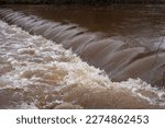 Small photo of Turbid brown water rolling over the spillway. Floods.
