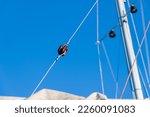 Small photo of A red-brown porcelain backstay insulator from a sailing yacht against a clear blue winter sky.