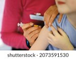 Small photo of A child about to be given the combined MMR (mumps, measles, rubella) vaccination into their arm by a surgery nurse with a hypodermic syringe, England, UK.