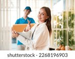 Caucasian businesswoman checklist online order best seller product and thumbs up about professional delivery while Asian worker man holding cardboard for shipping